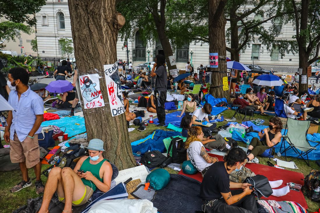 Protesters occupy the area outside of City Hall, with blankets, hammocks, signs, snacks, water
